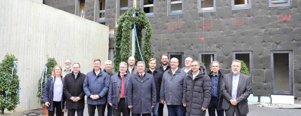 Bayerns Bauminister Christian Bernreiter (Mitte) vor der Richtkrone mit (v.l.) Christiane Hofer, derzeit stellvertretende Leiterin der JVA Amberg/Weiden und desiginierte Leiterin der JVA Passau, Passaus Oberbürgermeister Jürgen Dupper, MdL Stefan Meyer, MdL Josef Heisl, Prof. Dr. Gerhard Waschler, MdL Josef Zellmeier, Vorsitzender des Anstaltsbeirats, JVA-Leiter Marcus Hegele, MdL Toni Schuberl, MdL Tobias Beck, stv. Vorsitzender des Anstaltsbeirats, MdL Christian Lindinger, MdL Oskar Atzinger, Landrat Raimund Kneidinger, Architekt Ludwig Karl und Gerald Escherich, Bereichsleiter Hochbau am Staatlichen Bauamt Passau.